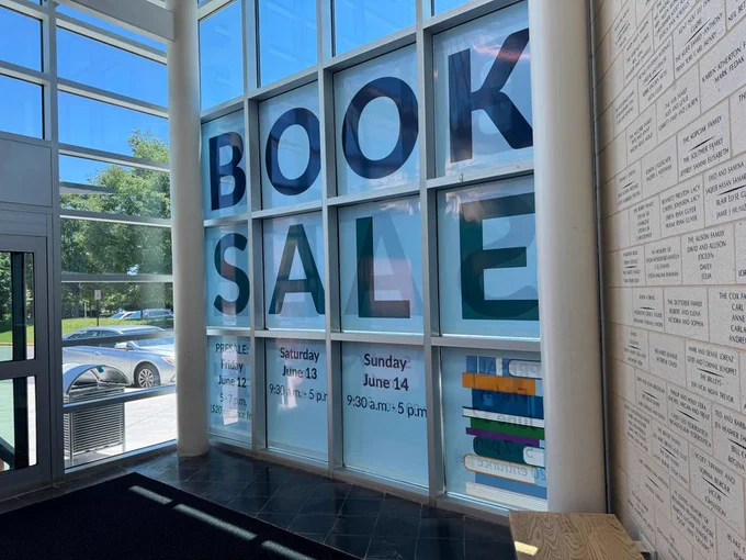 Book sale signage in Ashburn Library's lobby windows.