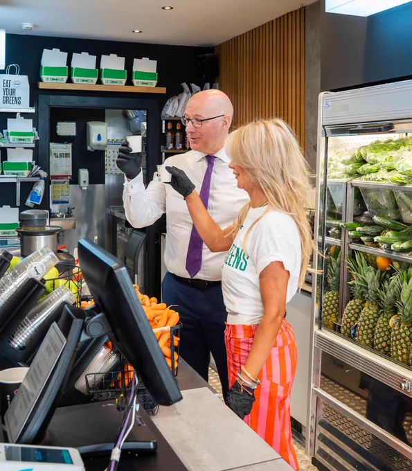 First Minister John Swinney holding a freshly made fruit drink with a young entrepreneur. 