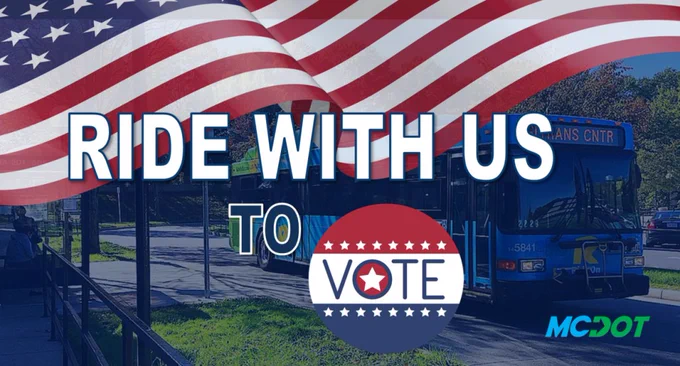 A blue bus at a stop with a large US flag and message promoting riding transit to the voting polls.