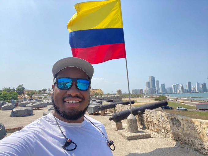Colin Howe taking a selfie in front of a Columbian flag. 