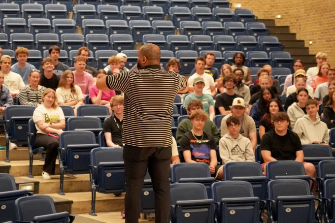 High school students and staff in a middle school auditorium for training about summer programs.