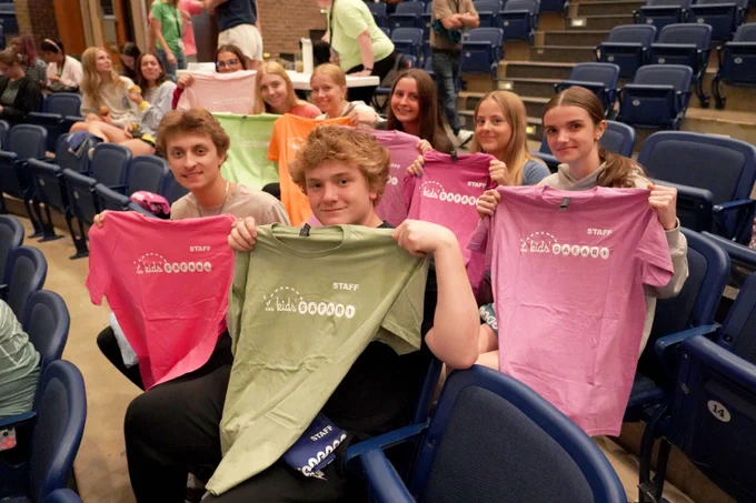 Eight high school students holding up Kids' SAFARI staff T-shirts at a training event for the summer program.