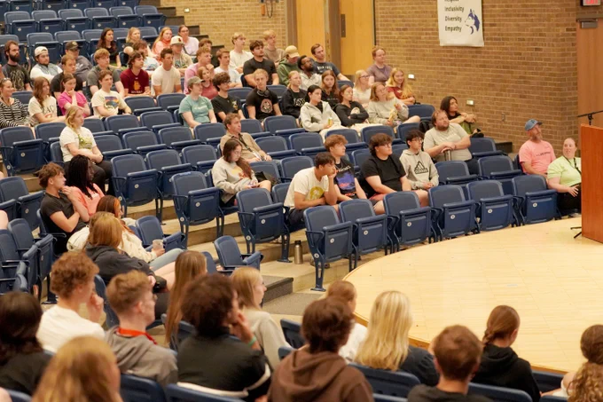 High school students and staff in a middle school auditorium for training about summer programs.