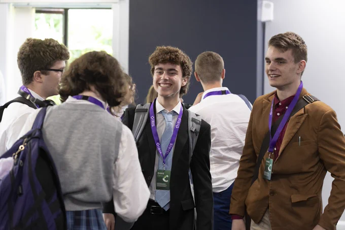 A group of students stand in conversation in a conference venue