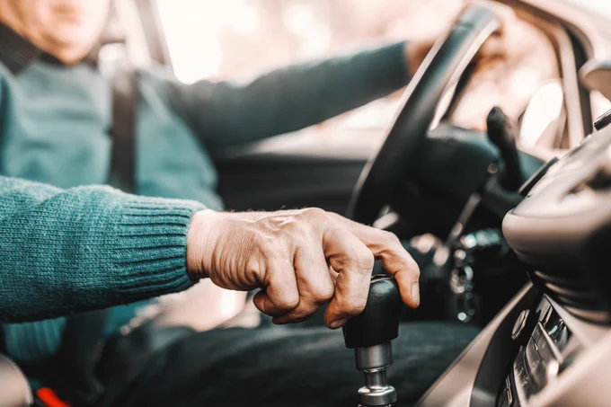 Elderly person driving with hand on gear shift