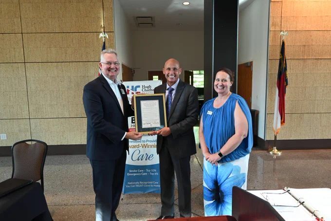 image of three people posing for photo; one person is holding a certificate