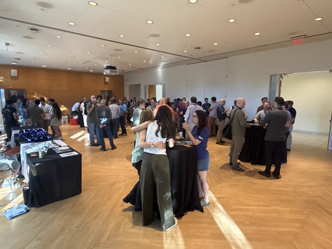 A crowded welcome reception for the Groundwater Modeling and More conference. The room is filled with a diverse group of attendees mingling, with registration tables visible on the left.