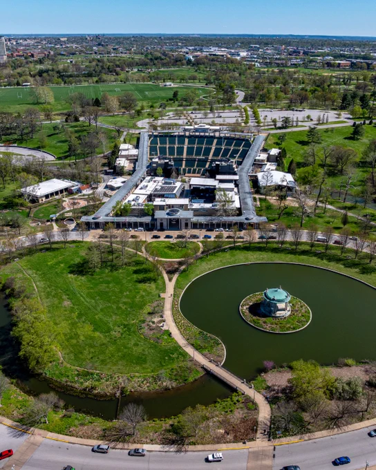 An aerial over Pagoda Circle in springtime shows the Muny, centered, and the Taylor Kindle River surrounds the Nathan Frank Bandstand island in the bottom right frame.