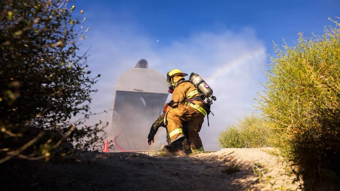 A firefighter carries a simulated casualty away from a training prop during aircraft rescue and firefighting training.