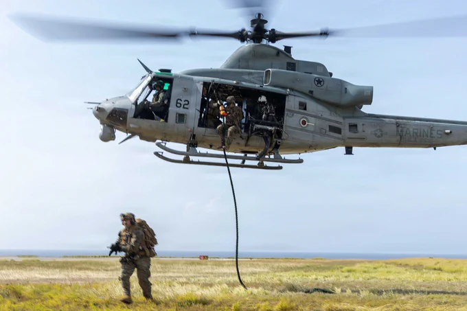 A U.S. Marine moves away from a UH-1Y Venom after descending by fast rope during helicopter insertion training.