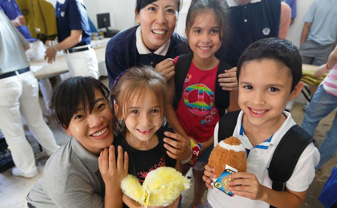 Smiling kids with new toys pose with smiling Tzu Chi personnel.