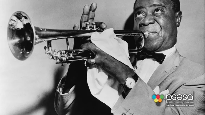 A photo of a male, middle-aged black musician playing his trumpet.
