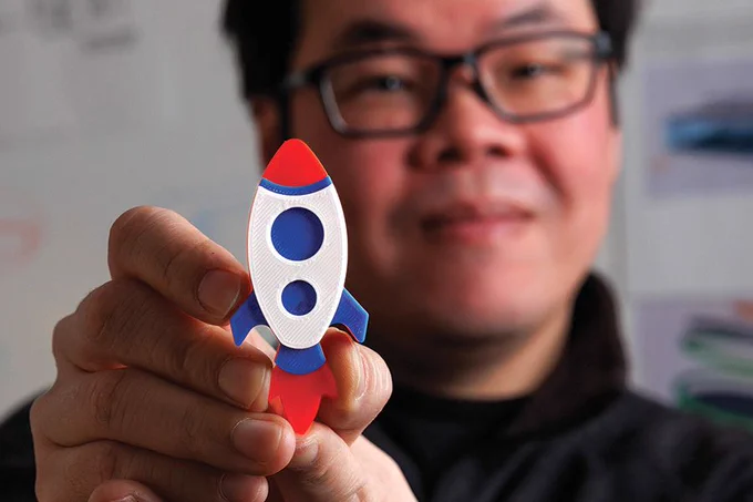 A researcher holds up a space shaped item close to the camera. 