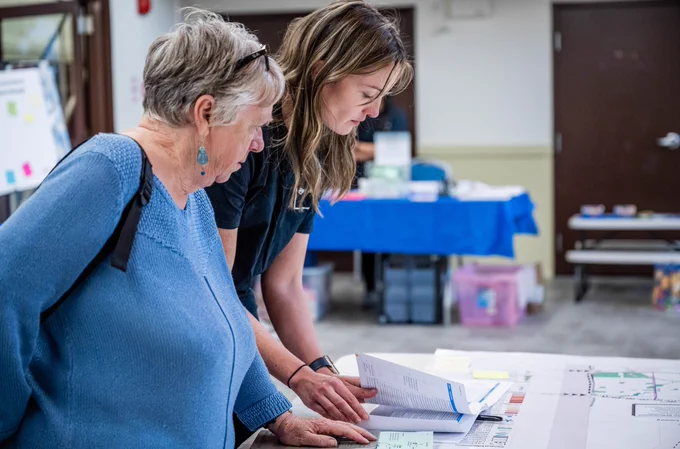 Two people talking over a table at an engagement open house. 