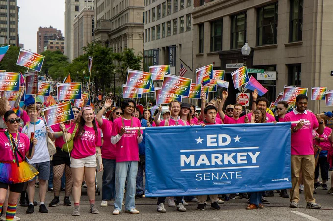 Team Markey organizers and volunteers cheer and hold rainbow signs.