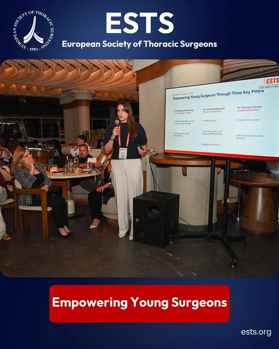 A speaker presents during the ESTS Women in General Thoracic Surgery and ESTS NextGen Networking Evening at DEOS Restaurant in Athens. She stands with a microphone beside a screen showing a presentation on empowering young surgeons through European networking, education, and training.