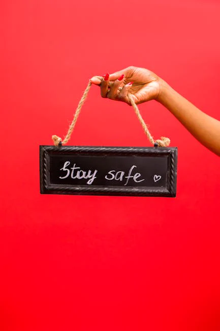 A hand holding a 'Stay Safe' sign on a bright red background for pandemic awareness.