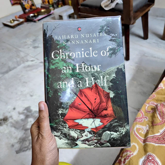 A hand holding the book 'Chronicle of an Hour and a Half' by Saharu Nusaiba Kannanari