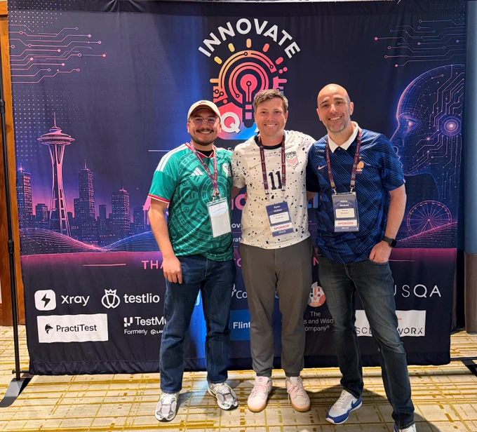 PLUS QA Team standing in front of Innovate QA Banner smiling at the camera. 