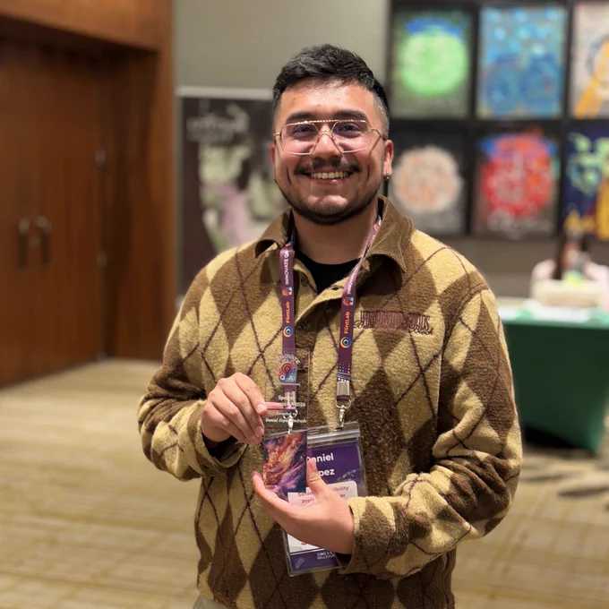 Photo of Daniel smiling at the camera holding his Speaker Award at Innovate QA. 
