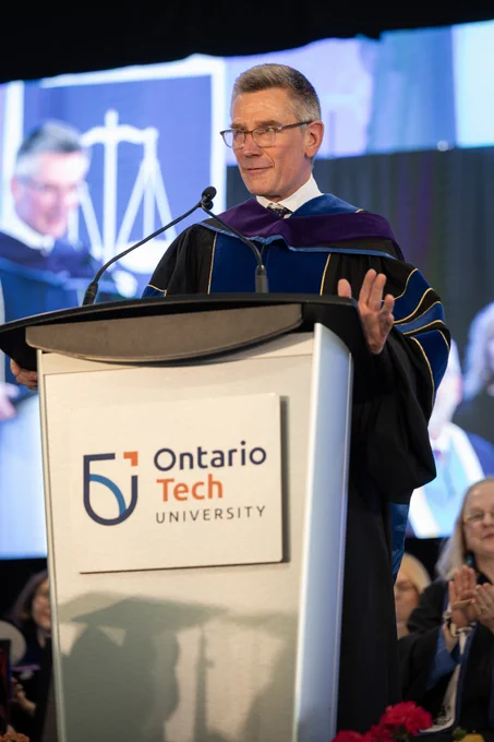 A photo of honorary degree recipient Nick Eaves, COO of Maple Leaf Sports & Entertainment, sharing his remarks at an Ontario Tech branded podium during the 2026 Spring Convocation ceremony.
