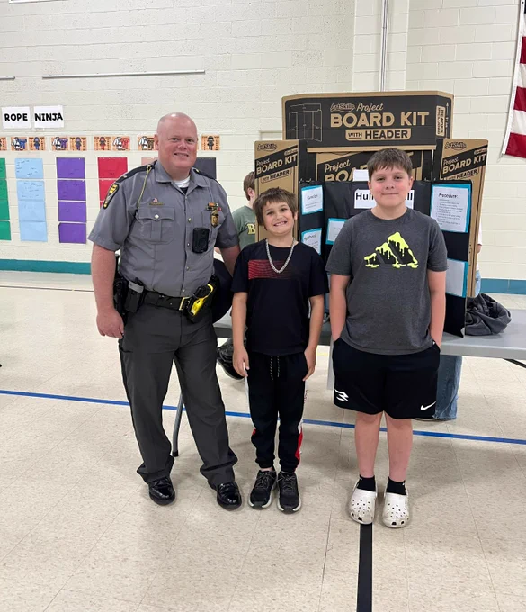 Lt. Morrison joins two students next to their science fair project. 
