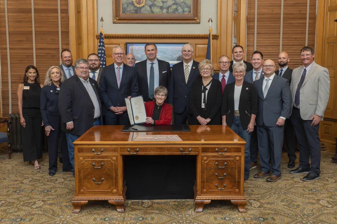 Kansas Governor Laura Kelly and group of professionals smiling at the ceremonial billing signing of SB 82.