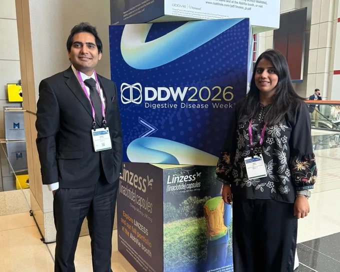 Two conference attendees wearing badges stand beside a DDW 2026 (Digestive Disease Week) promotional sign.
