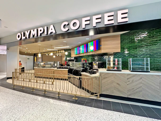 Olympia Coffee shop with wooden counters and dark green tiled walls under bold signage.