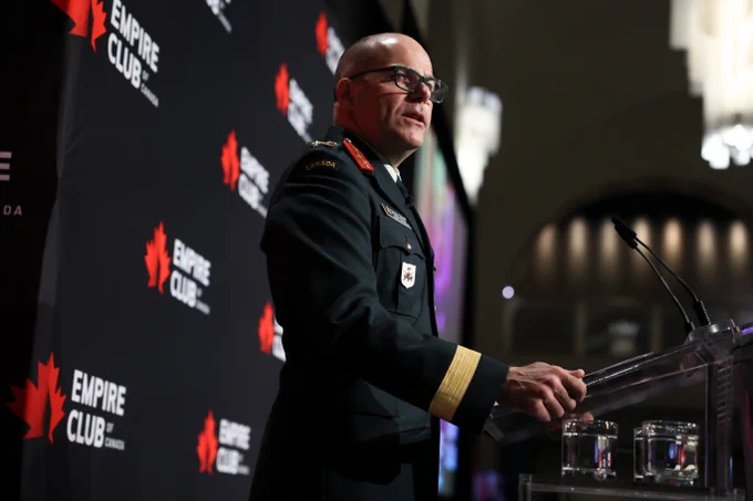 Military officer in uniform speaking at a podium during an event.