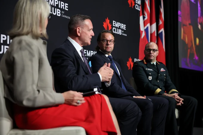 Four panelists seated on stage during an event.