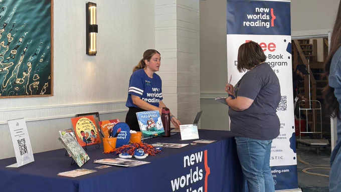 A person speaking to an educator at a New Worlds Reading table. 