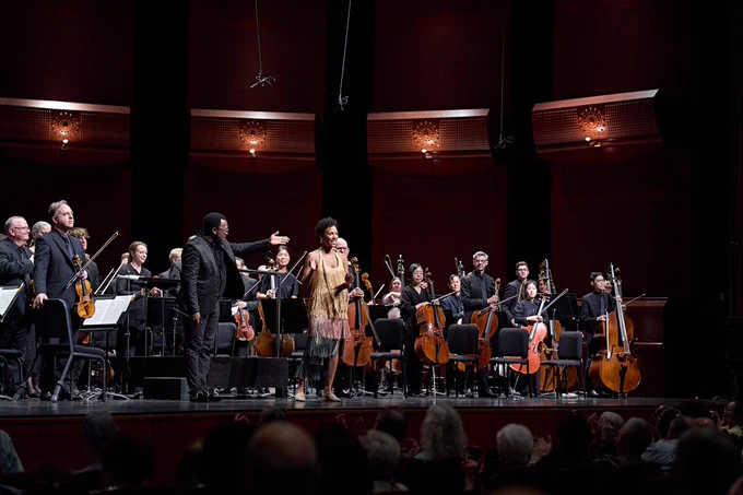 Colton Conducting Fellow Gregory D. McDaniel and New Jersey Symphony musicians standing for applause with Resident Artistic Partner Allison Loggins-Hull.