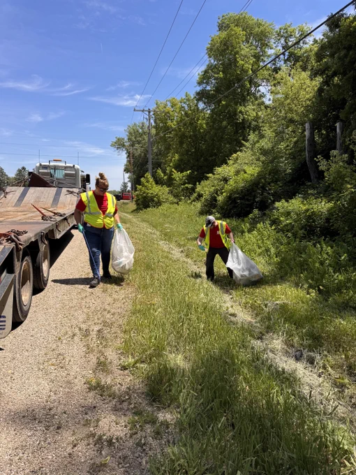Two Hydrite employees use grabbers to remove trash from roadway.