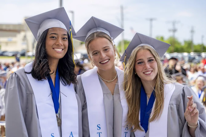 Three Rose State College graduates smile for a photo in their caps and gowns before graduation.