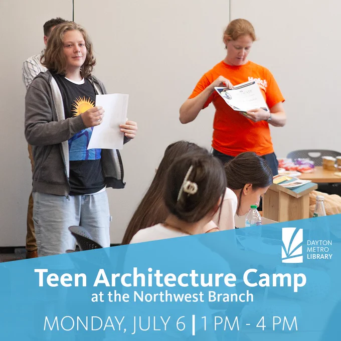 A teen stands holding papers while an instructor in an orange shirt hands out certificates in a classroom. Other teens sit at tables in the foreground, with art supplies and materials visible.
