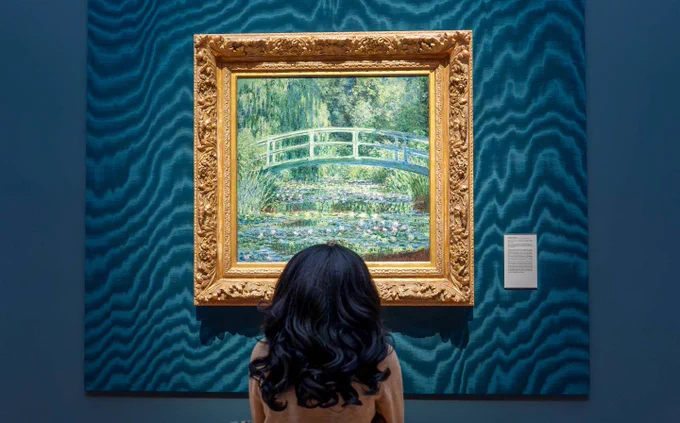 A person sits in front of Claude Monet’s “Water Lilies and Japanese Bridge”