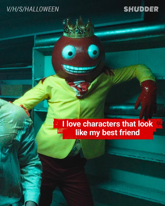 A humorous and spooky scene featuring a character with a red head and wide grin in a basement setting, wearing a yellow suit and a crown.