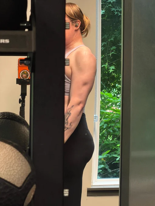 woman at the gym with the curve of her back arms ass and legs in the mirror