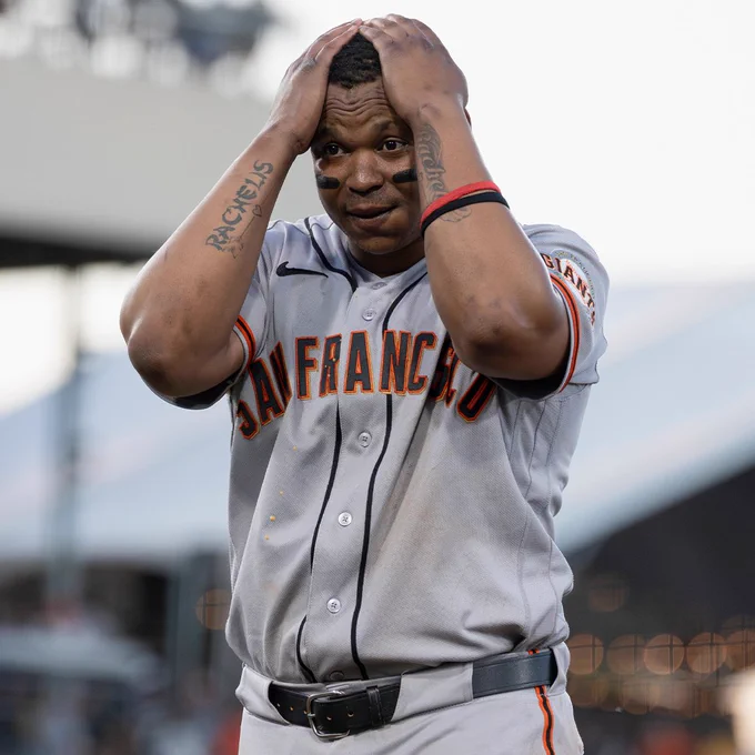 Rafael Devers holds both hands on his head and has a shocked expression on his face. He is wearing a gray San Francisco Giants jersey.
