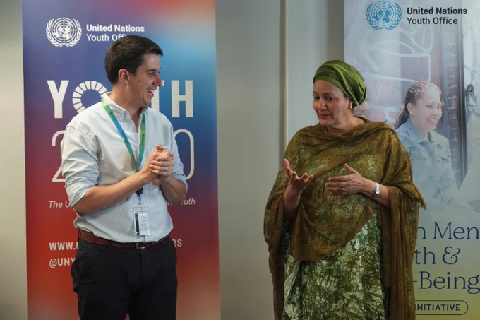 The Assistant Secretary-General for Youth Affairs in conversation with the Deputy Secretary-General at the United Nations Youth Office, standing near banners promoting youth initiatives.
