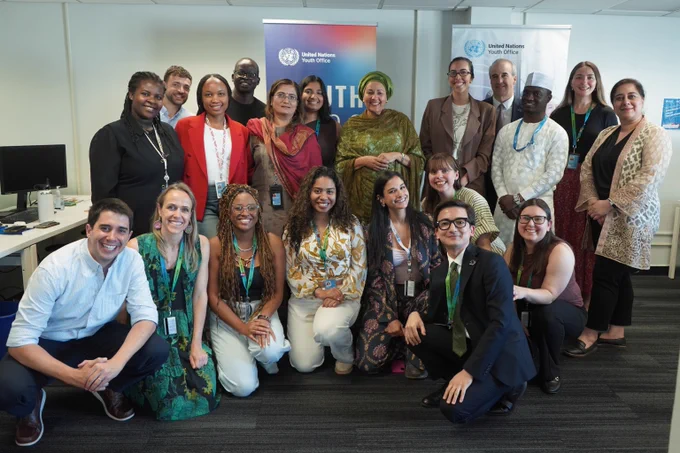 A group of diverse staff at the United Nations Youth Office posing together with the UN Deputy Secretary-General at the United Nations Youth Office event indoors.
