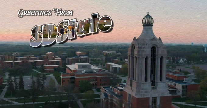 A scenic view of South Dakota State University campus at sunrise, featuring the Sylvan Theatre and iconic Coughlin Campanile in the foreground. The image has a textured, postcard-like design with the text "Greetings From SDState" prominently displayed in the top left corner.