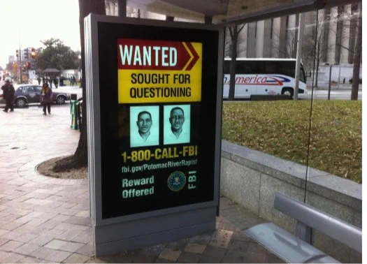 A photo of a digital billboard was used by the FBI to share information about fugitives, with information on how to reach the FBI by calling 1-800-CALL-FBI.