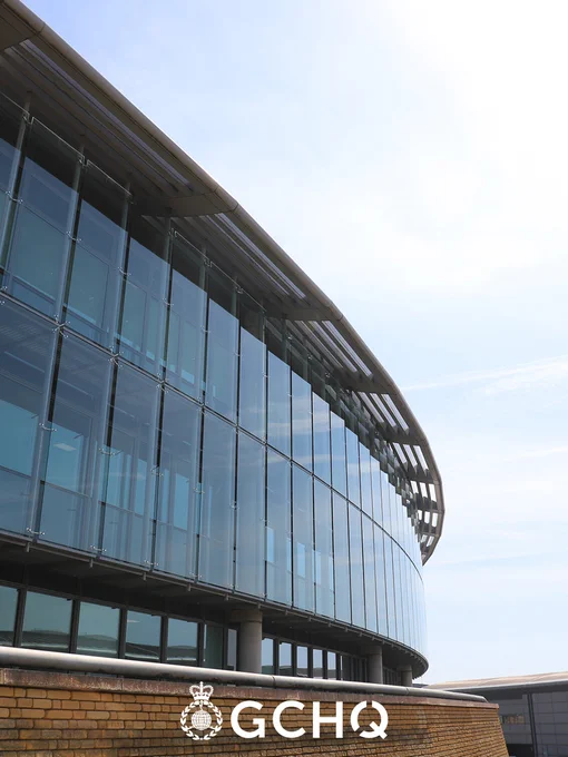 Exterior view of the modern, curved architecture of the GCHQ building under a clear sky.