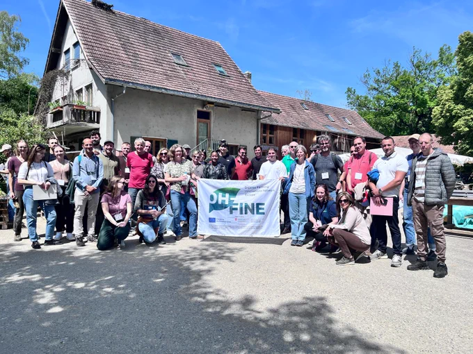 The project members pose with the OH‑FINE banner on a farm.