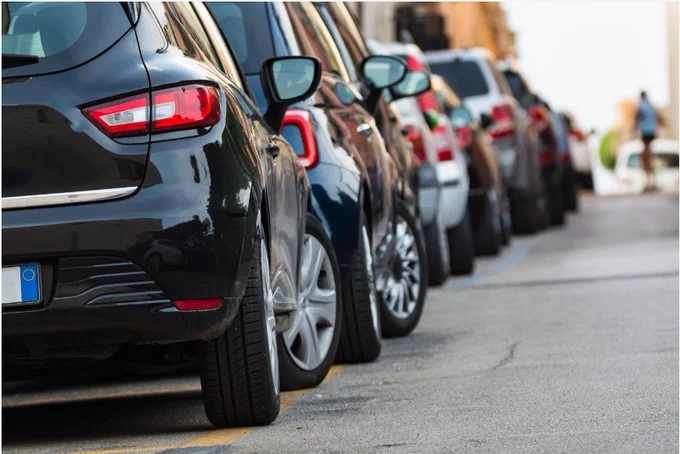 A line of parked cars, viewed from the rear, on a street.