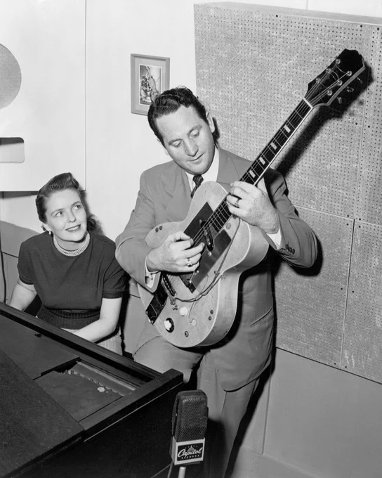 Les Paul playing a guitar with a Capitol Records label, while Mary Ford sits at a piano in a recording studio.
