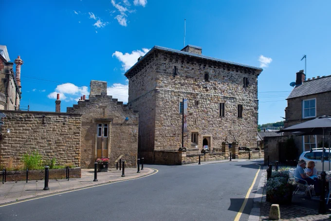 The exterior of a large historic stone building with blue sky behind it.