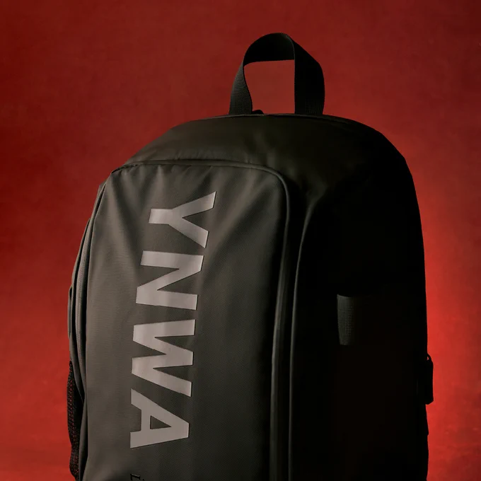 Black Liverpool FC backpack standing upright against a red backdrop, with bold “YNWA” lettering printed vertically on the front.